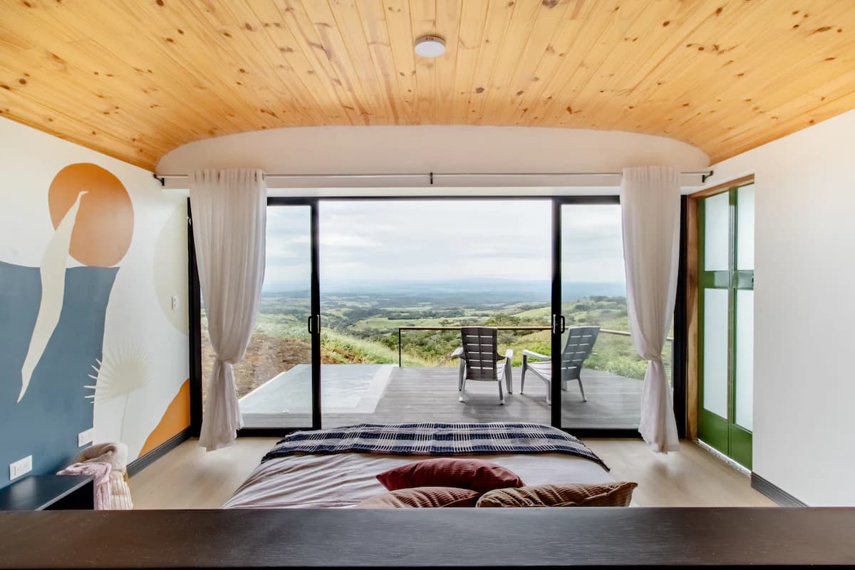 Bed facing floor-to-ceiling glass and the valley